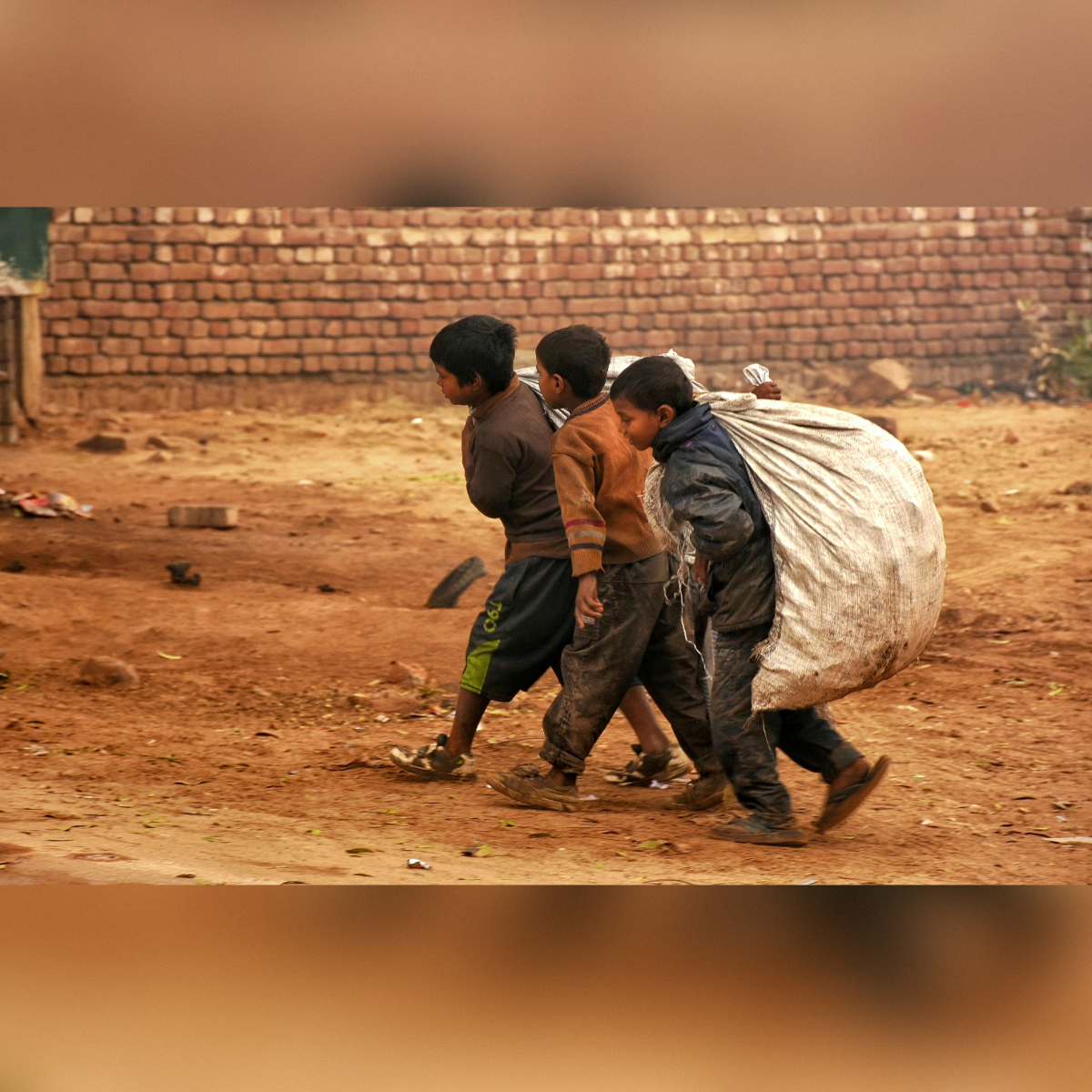 Tre bambini che camminano lungo una strada sterrata